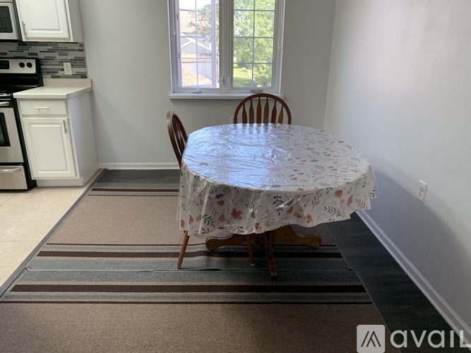 A dining room with a round table covered in a floral tablecloth and two chairs.