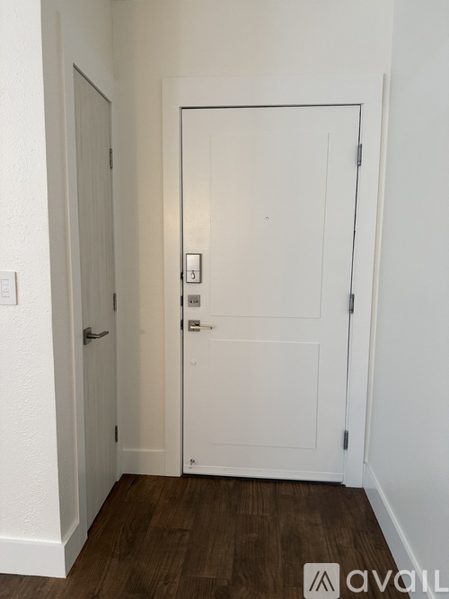 A white door with a silver handle and a lock is in a room with wooden flooring.