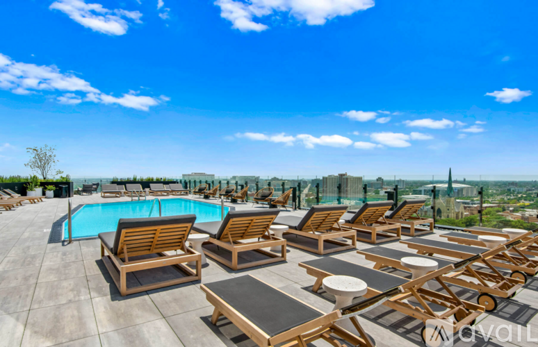 A rooftop pool area with sun loungers and a view of the city.