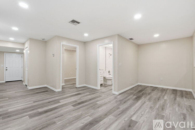 A spacious room with wooden flooring and white walls.