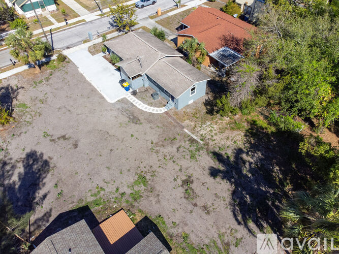 A bird's eye view of a house with a grey roof and a blue shed.