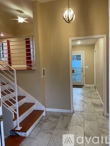 A hallway with a staircase and a door leading to a balcony.