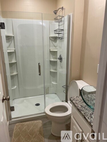 A white toilet with a glass shower door in a bathroom.