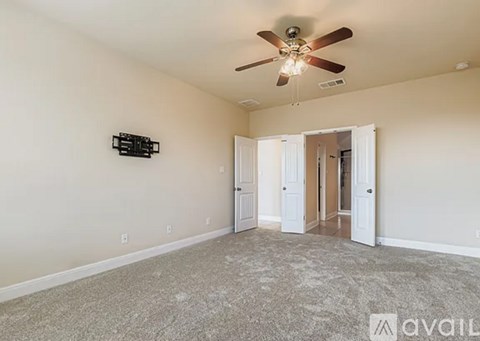 A spacious room with a ceiling fan and a carpeted floor.