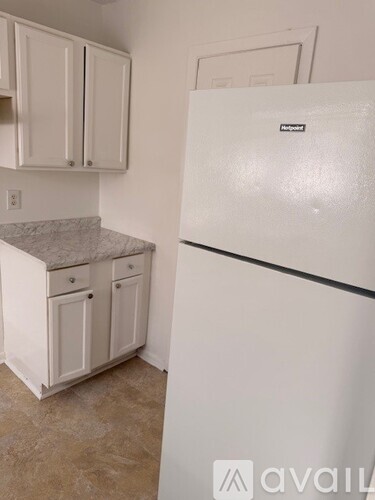 A white Kenmore refrigerator in a kitchen with white cabinets.