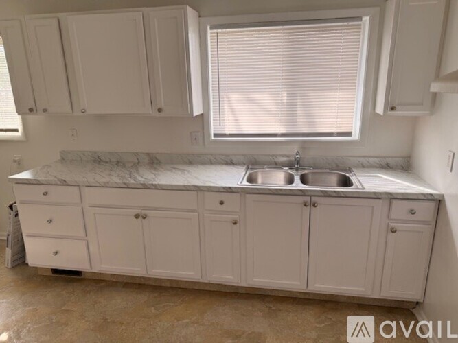 A kitchen with white cabinets and a marble countertop.