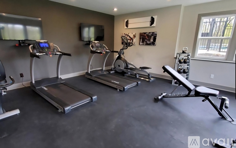 A gym with treadmills, exercise bikes, and a rowing machine.