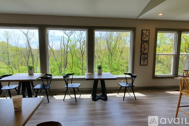 A dining room with a view of the trees outside the large windows.