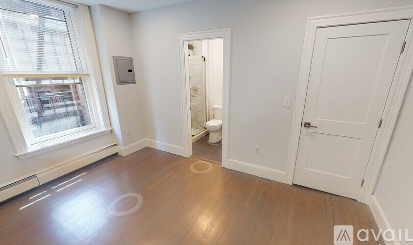 A room with a wooden floor and a window with blinds.