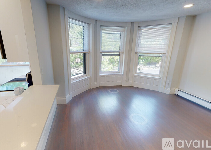 A room with a white countertop and wooden flooring with three windows.