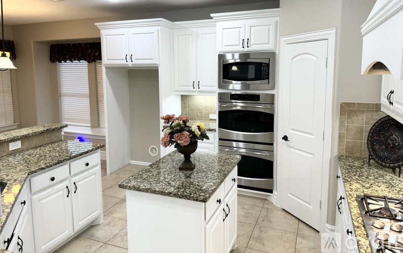A kitchen with white cabinets and granite countertops.