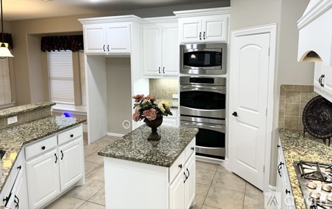 A kitchen with white cabinets and granite countertops.
