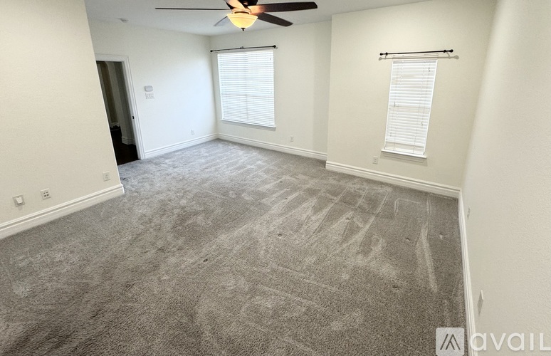 A spacious room with a ceiling fan and carpeted floor.