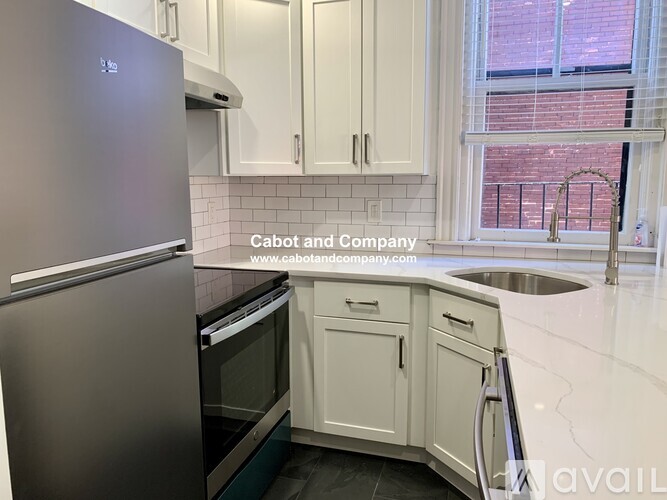 A kitchen with a stainless steel refrigerator and white cabinets.
