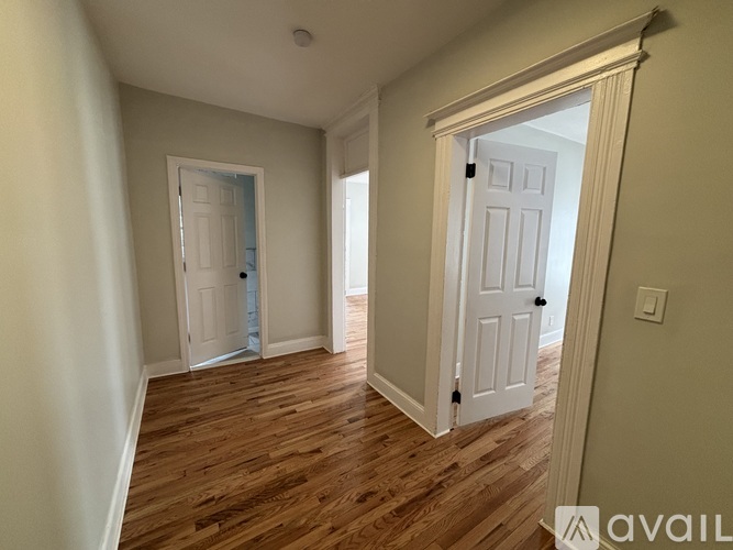 A room with a white door and a wooden floor.
