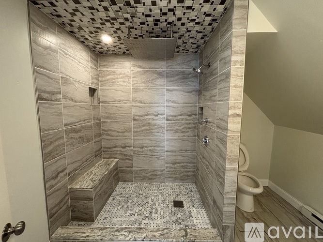 A bathroom with a marble tile shower and a tiled floor.