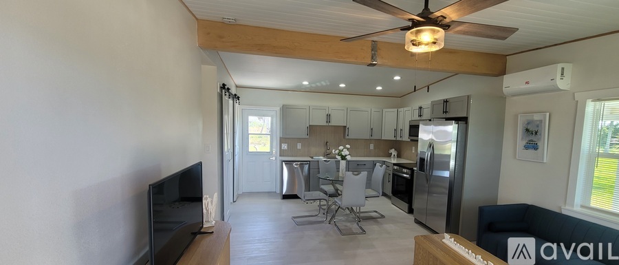 A modern kitchen with a refrigerator, sink, and a dining table with chairs.