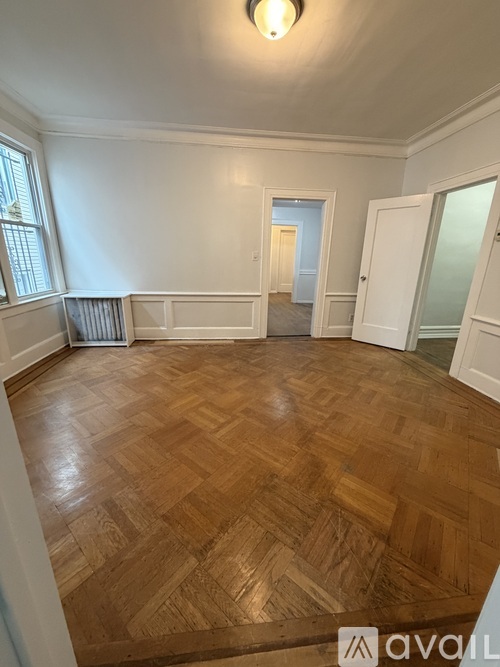 A room with wooden flooring and white walls.