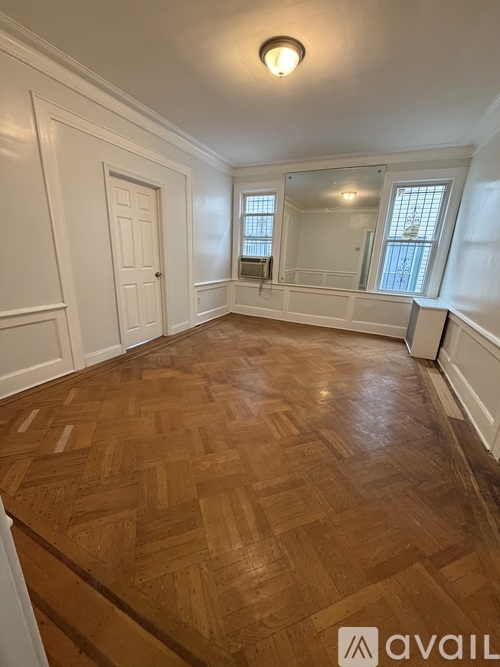 A room with wooden flooring and white walls.