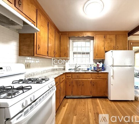 A kitchen with wooden cabinets and a white stove top oven.