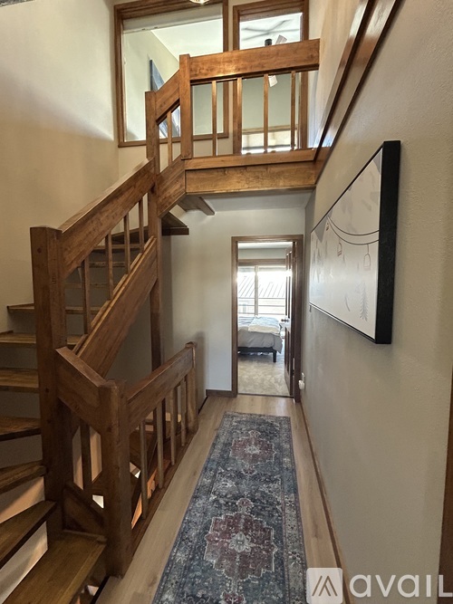 A wooden staircase with a glass balustrade leads to a landing with a doorway.