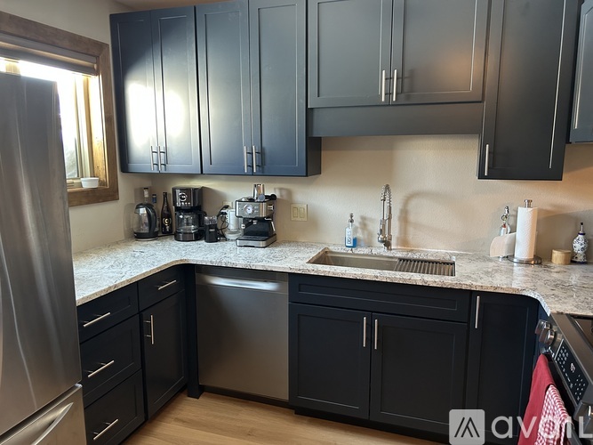A kitchen with black cabinets and a granite countertop.