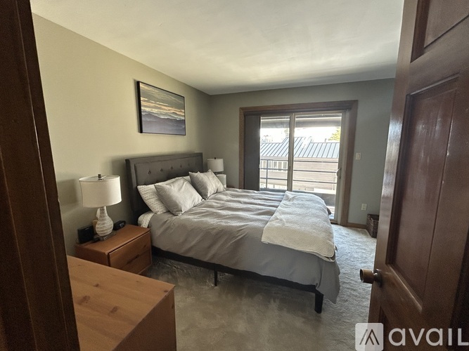 A bedroom with a large bed and a wooden nightstand.