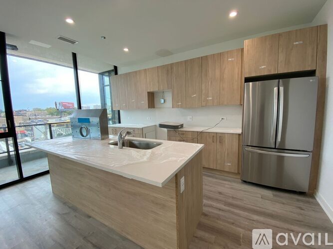 A modern kitchen with wooden cabinets and a stainless steel refrigerator.