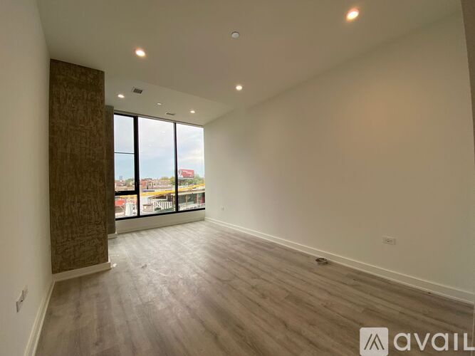 A spacious room with wooden flooring and large windows overlooking a cityscape.