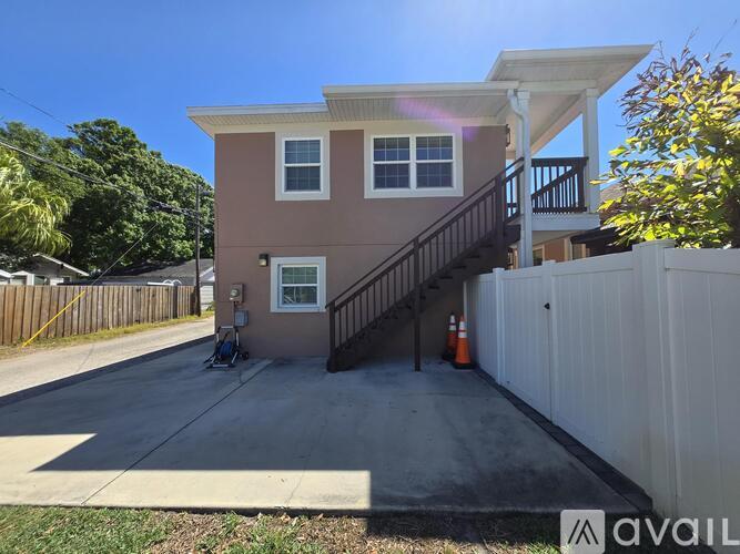A house with a brown and beige exterior has a black staircase leading to the second floor.