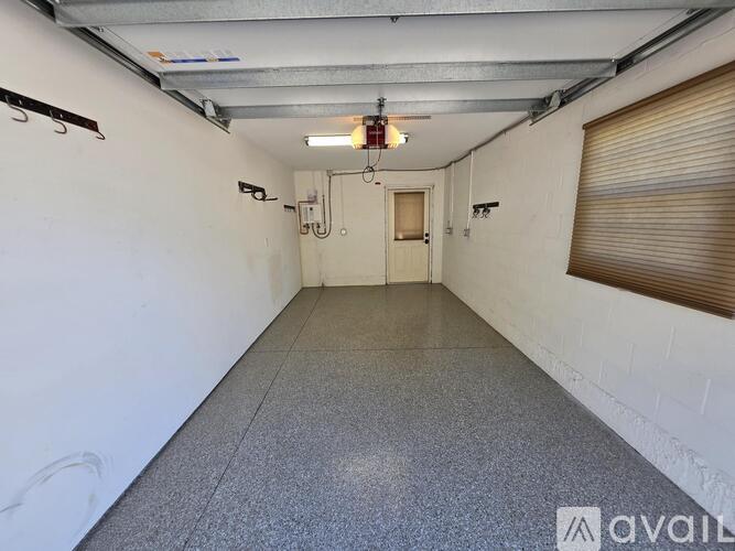 A long, narrow hallway with a door at the end and a light fixture hanging from the ceiling.