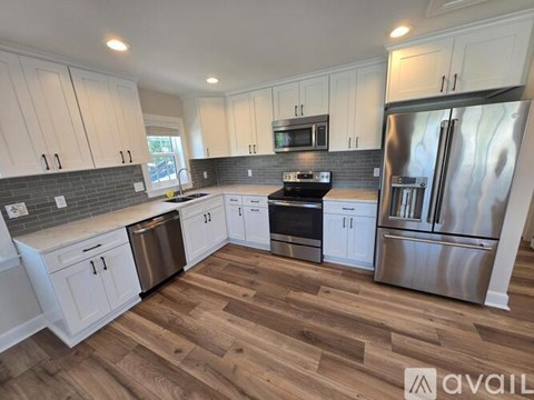 A kitchen with white cabinets and a wooden floor.