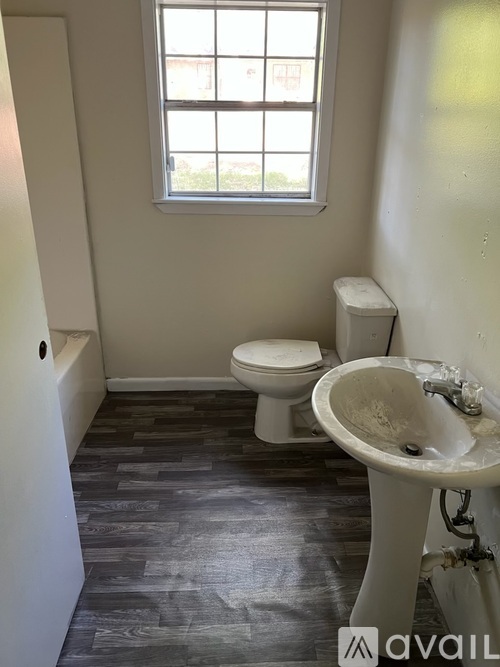 A bathroom with a toilet, sink, and window.