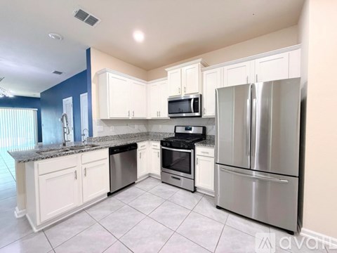 A kitchen with white cabinets and a stainless steel refrigerator.