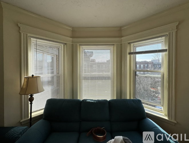 A blue couch sits in front of a window with blinds.
