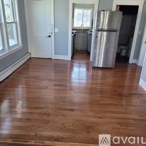 A kitchen with a wooden floor and a refrigerator.
