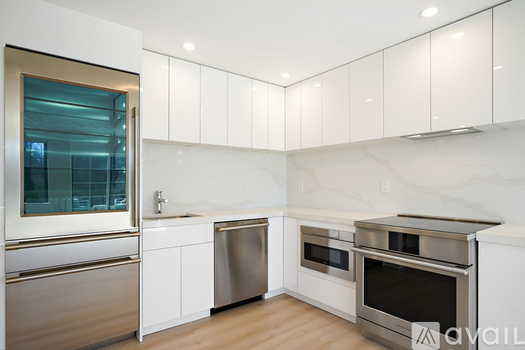 A modern kitchen with white cabinets and stainless steel appliances.