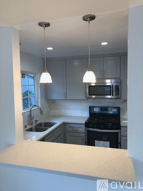A kitchen with a white countertop and grey cabinets.