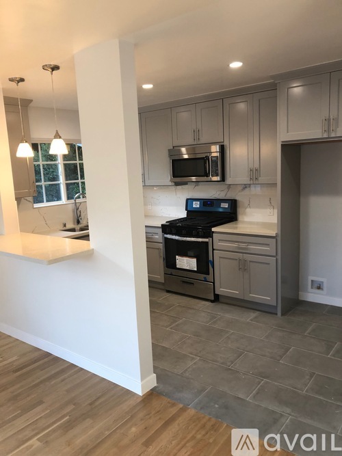 A kitchen with a black oven and wooden flooring.