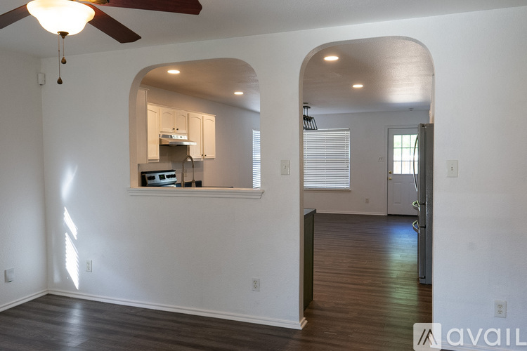 A spacious living room with a ceiling fan and hardwood floors.