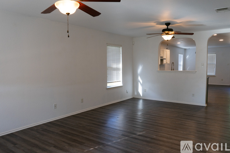 A spacious room with a ceiling fan and hardwood flooring.