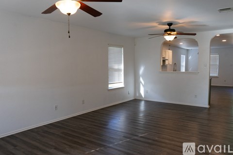 A spacious room with a ceiling fan and hardwood flooring.
