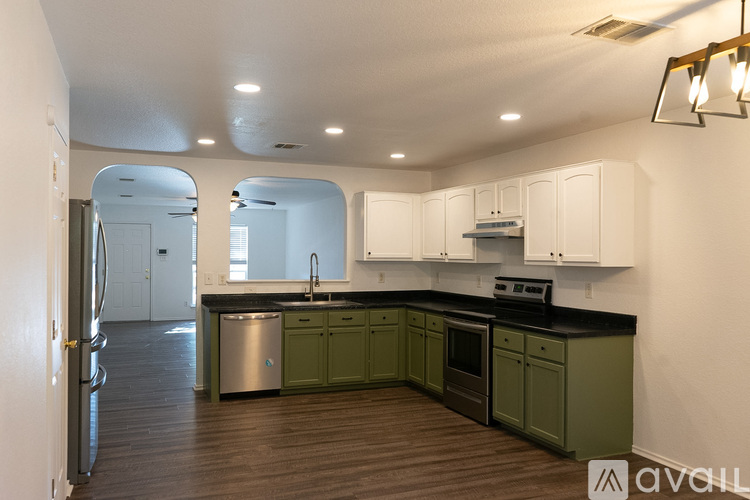 A kitchen with green cabinets and a stainless steel sink.