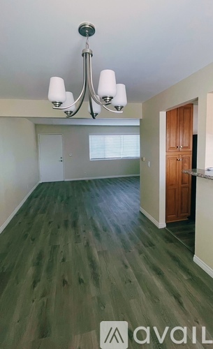 A room with a chandelier and wood flooring.