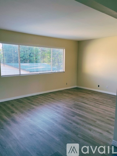 A room with wooden flooring and a window with blinds.