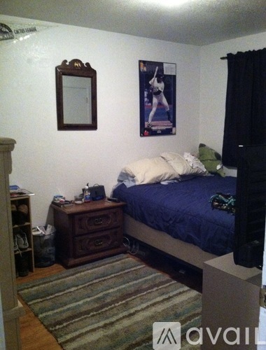 A bedroom with a bed, nightstand, and a poster on the wall.