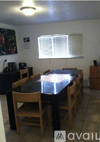 A dining room with a black table and chairs.