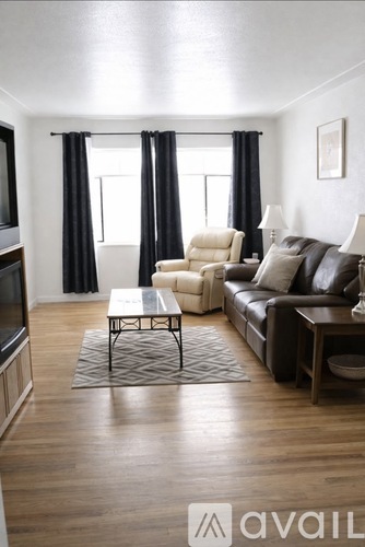 A living room with a brown leather couch and a white chair.