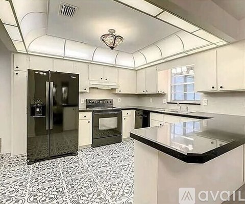 A kitchen with black and white tiles and a black fridge.