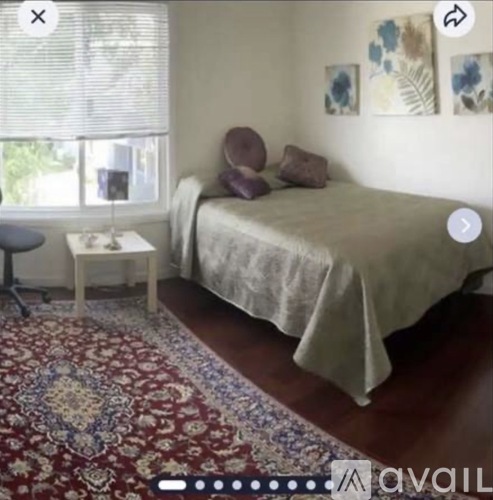 A bedroom with a bed, a chair, and a rug.
